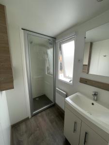 ein Bad mit einer Dusche, einem Waschbecken und einem Spiegel in der Unterkunft Valras-Plage, les sables du midi ,mobil home in Sérignan