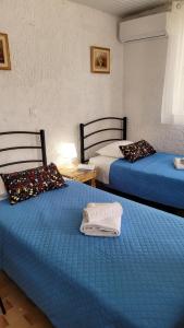 two beds in a room with blue sheets at G&A Rooms Marmari in Marmari