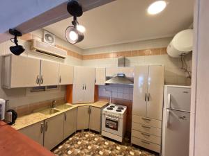 eine Küche mit weißen Schränken, einem Herd und einem Kühlschrank in der Unterkunft شالهيات درة العروس in Durrat Al-Arus