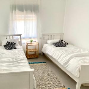 2 camas blancas en una habitación con ventana en יפעת הגלבוע -צימר משפחתי וזוגי מפנק בגלבוע, en Nurit