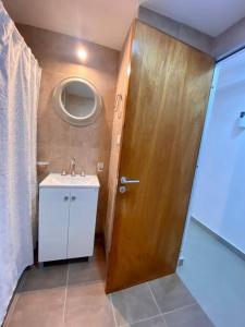 een badkamer met een houten deur en een wastafel bij Terrazas 2002 Confortable Monoambiente in Salta