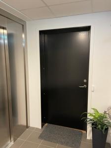 a black door in a room with a plant at Ocean view apartment in Tromsø