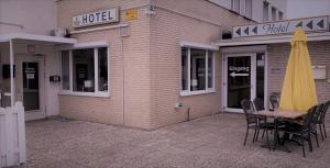 een tafel en stoelen buiten een hotel met een gele paraplu bij Hotel am Hafen in Braunschweig
