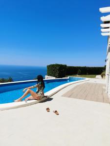 a woman sitting next to a swimming pool at Lux Villa Provence in Budva