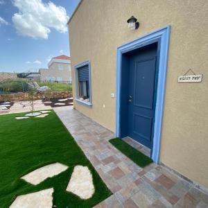 une porte bleue sur une maison avec une cour dans l'établissement יפעת הגלבוע -צימר משפחתי וזוגי מפנק בגלבוע, à Nurit