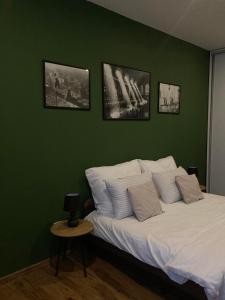 um quarto com paredes verdes e uma cama com almofadas brancas em Dovolenkový dom eLAra em Smizany