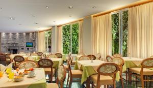 a dining room with tables and chairs and windows at Dioni Hotel in Ioannina