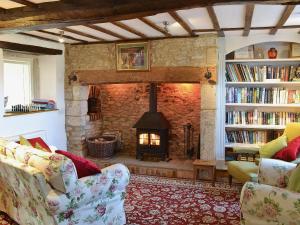 uma sala de estar com lareira, sofá e livros em Rose Cottage em Cold Ashton