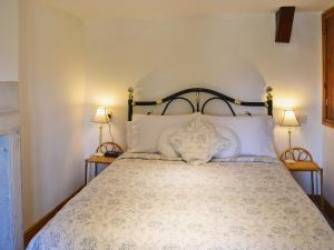 a bedroom with a large bed with two lamps at Rose Cottage in Cold Ashton