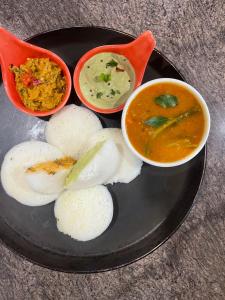 um prato de comida com duas tigelas de sopa e arroz em Royal Suites - 3 BHK - Neo em Pune