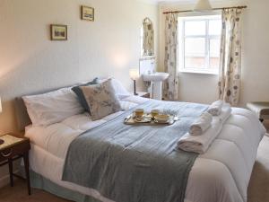 a bedroom with a bed with a tray of food on it at Farm Cottage annex in Smallburgh