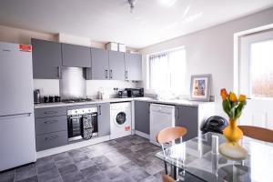 a kitchen with white appliances and a glass table at Stunning canal view 2 bedroom home with free parking in Manchester