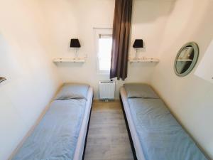 two beds in a small room with a window at Sandy Feet Retreat in Petten