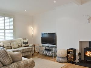 een woonkamer met een bank, een tv en een open haard bij Nautilus Cottage in Cellardyke