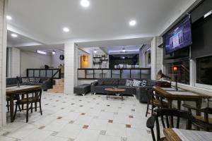 un soggiorno con divani, tavoli e TV di MELODİ BUTİK OTEL a Edremit