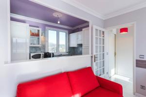 een rode bank in een kamer met een keuken bij Grand 2 pièces proche Mer et Hippodrome in Cagnes-sur-Mer