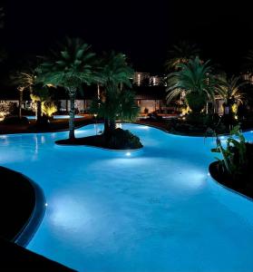 a large blue pool with palm trees at night at 9th floor 2BR 2 BATH King Suite Beach shuttle, heated pool! in Destin