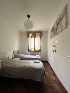 1 dormitorio con 2 camas y ventana en Appartamento al piano terra vicino all’aeroporto., en Quinto di Treviso