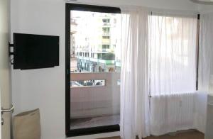 a room with a window with white curtains and a television at M007-8-9 Marquer Chambre colocation proche de la Gare in Annemasse