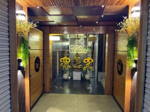 una puerta delantera de un hotel con flores amarillas en Hotel Sabera en Siliguri