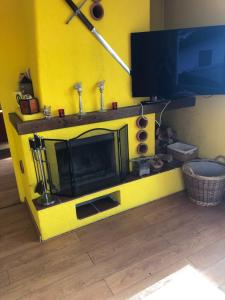 un salon jaune avec une télévision et un mur jaune dans l'établissement Inspiration über dem See, à Locarno