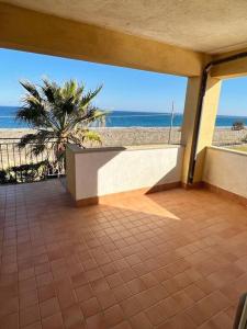 d'un balcon avec vue sur une plage bordée d'un palmier. dans l'établissement Casa vicino al mare, à Bianco