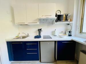 una cucina con mobili blu e un lavandino di Studio au bord de mer 1 a Mentone Altre 3 foto