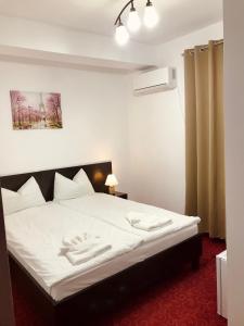 een slaapkamer met een wit bed en 2 handdoeken bij Apartamente 9 - Naomi in Baile Felix