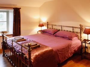 a bedroom with a large bed with purple sheets at Higher Thorne Cottage - 28297 in Warleggan