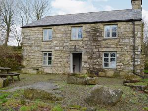 an old stone house with a bench in front of it at Higher Thorne Cottage - 28297 in Warleggan