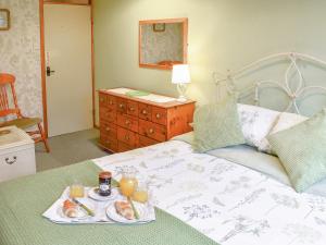 a bedroom with a bed with a tray of food on it at Woodbine Cottage in Ludham