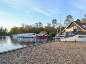 a group of boats docked at a house on a river at Woodbine Cottage in Ludham