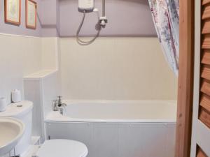 a bathroom with a tub and a toilet and a sink at Woodbine Cottage in Ludham