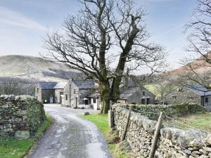 a country road in a village with a stone wall at Riverbank Cottage-uk42229 in Low Borrowbridge