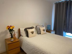 een slaapkamer met een bed met kussens en een vaas met bloemen bij Edinburgh Apartment BR in Edinburgh