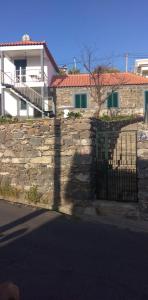 uma parede de pedra com um portão em frente a uma casa em Casa do Avô em Ponta do Sol