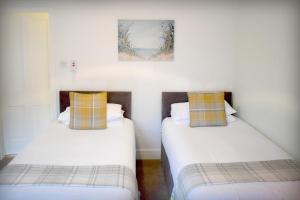 two beds in a room with white walls at The ‘Servants Quarters@Delny House’ in Invergordon