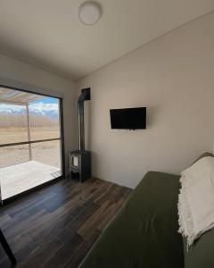 1 dormitorio con 1 cama y TV de pantalla plana en MODERNAS CABAÑAS EN USPALLATA en Uspallata