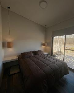 1 dormitorio con cama y ventana grande en MODERNAS CABAÑAS EN USPALLATA en Uspallata