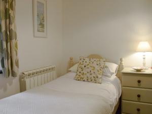a bedroom with a bed and a dresser with a lamp at Ivy Cottage in Henllan