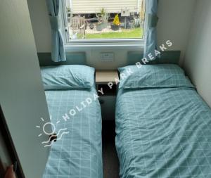 Spacious 3 bed @ Seal Bay Resort (Bunn Leisure) في سيلسيه: سريرين في غرفة صغيرة مع نافذة