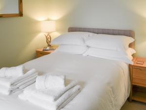 a bedroom with a white bed with towels on it at Addycombe Cottage in Rothbury