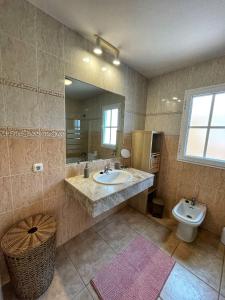 een badkamer met een wastafel, een toilet en een spiegel bij Villa Katerina in Caleta De Fuste