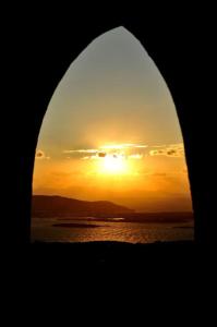 una vista de la puesta de sol a través de un arco de una ventana en Paros traditional house en Episkopianá