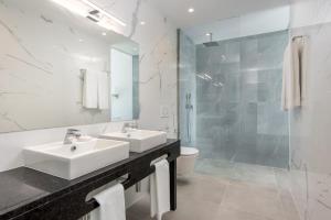 biała łazienka z 2 umywalkami i prysznicem w obiekcie Vila Luna B&B w Lagosie