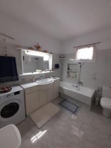 y baño blanco con lavabo, aseo y bañera. en Paros traditional house en Episkopianá