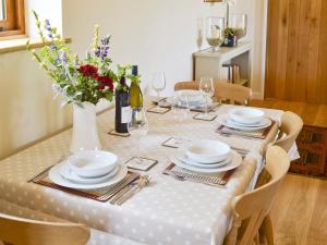 una mesa con un mantel blanco y un jarrón con flores en The Peacock Barn, en Burwash