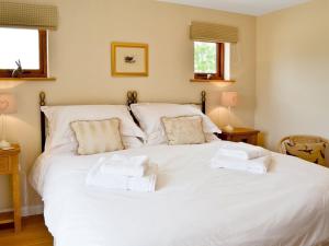 a bedroom with a large white bed with towels on it at The Peacock Barn in Burwash