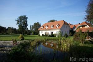 uma casa com um lago em frente em Hotel Zsida em Szentgotthárd