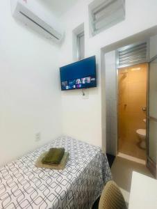 a bedroom with a bed and a tv on the wall at Suíte privada no melhor do Leblon in Rio de Janeiro